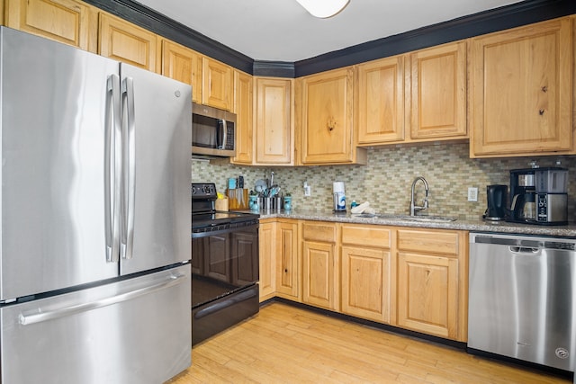 kitchen featuring tasteful backsplash, appliances with stainless steel finishes, sink, light wood-type flooring, and light stone counters