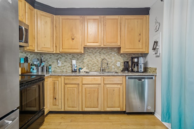 kitchen with sink, tasteful backsplash, appliances with stainless steel finishes, and light hardwood / wood-style flooring