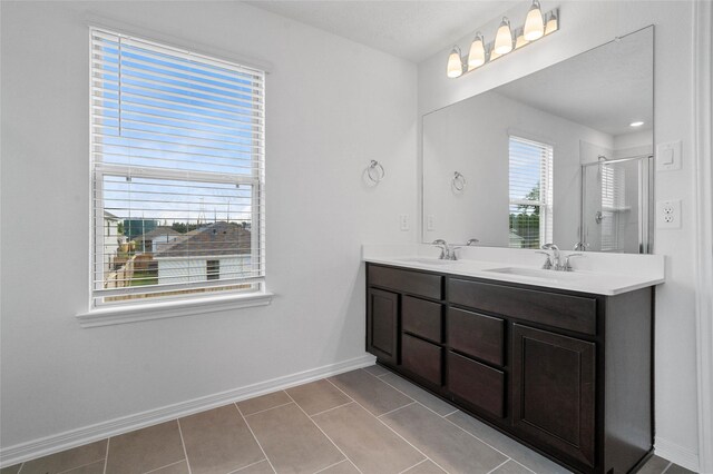 bathroom with a shower with door, vanity, and tile patterned flooring