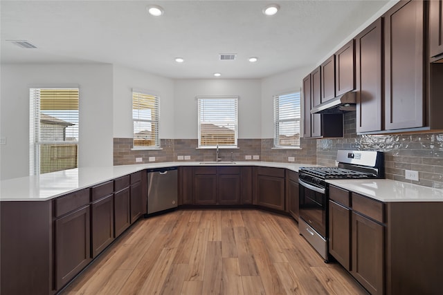 kitchen with kitchen peninsula, a healthy amount of sunlight, light wood-type flooring, and appliances with stainless steel finishes