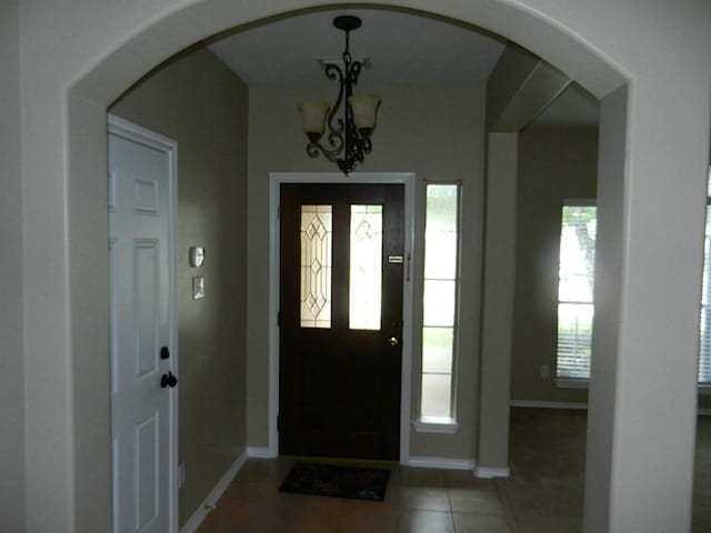 tiled foyer with a notable chandelier