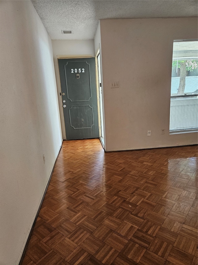 foyer entrance featuring dark parquet flooring and a textured ceiling