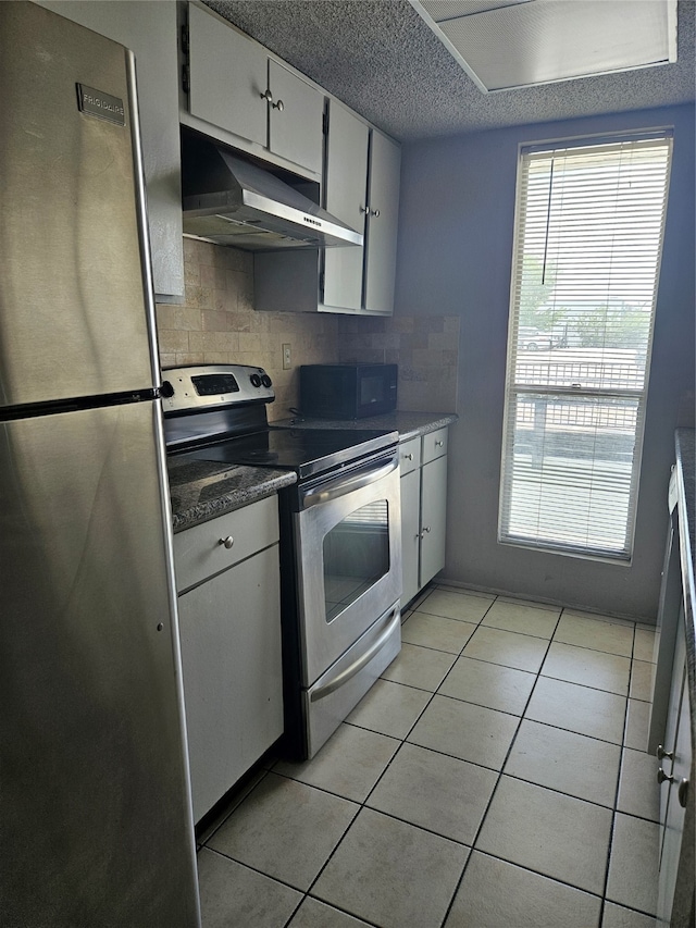 kitchen featuring backsplash, light tile floors, stainless steel appliances, and a textured ceiling