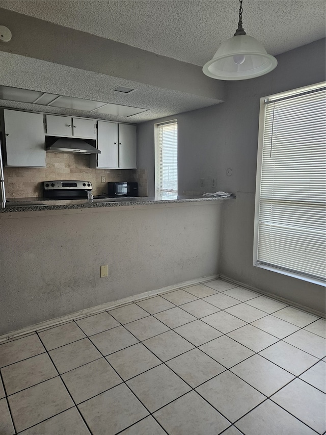 kitchen with light tile flooring, stainless steel electric range oven, a textured ceiling, tasteful backsplash, and pendant lighting