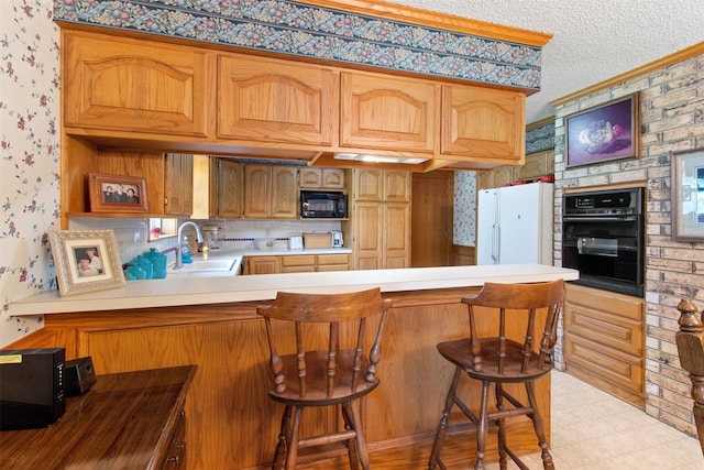 kitchen featuring kitchen peninsula, a breakfast bar, black appliances, and a textured ceiling