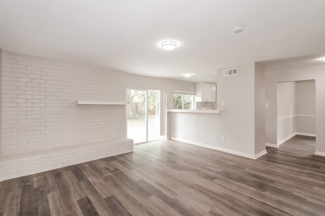 spare room featuring dark wood-type flooring and brick wall