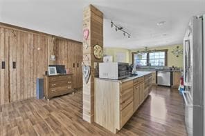 kitchen featuring wooden walls, appliances with stainless steel finishes, track lighting, and dark hardwood / wood-style floors