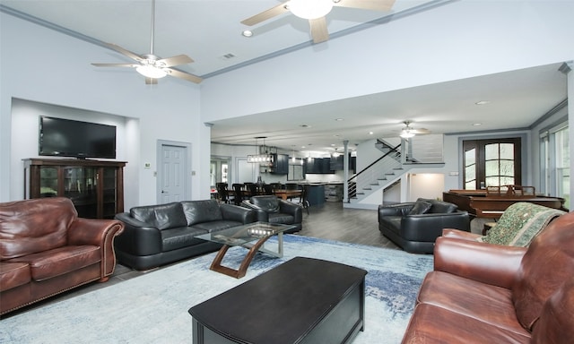 living room with a high ceiling, wood-type flooring, and ceiling fan with notable chandelier