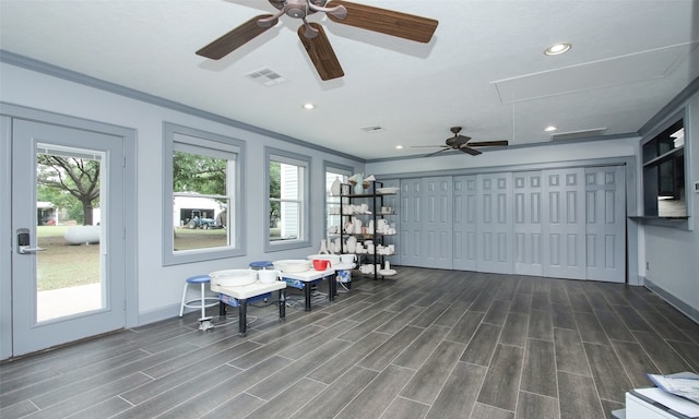 living area with crown molding, plenty of natural light, ceiling fan, and dark hardwood / wood-style flooring