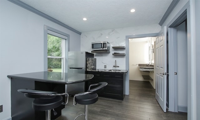 kitchen featuring crown molding, dark hardwood / wood-style flooring, a textured ceiling, sink, and appliances with stainless steel finishes