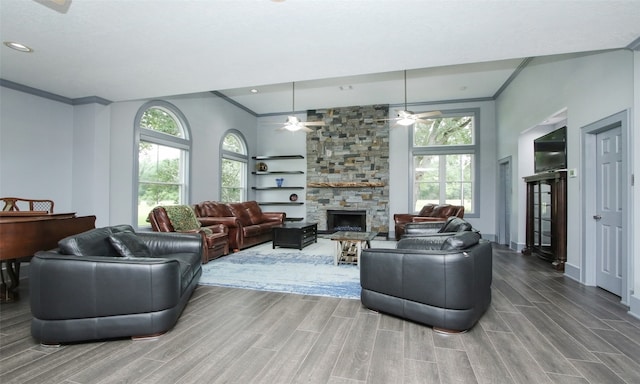 living room with wood-type flooring, a stone fireplace, ceiling fan, and crown molding