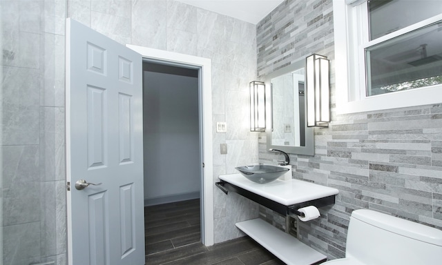 bathroom featuring sink, hardwood / wood-style floors, toilet, and tile walls