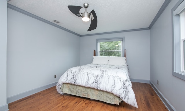 bedroom with dark hardwood / wood-style floors, ceiling fan, a textured ceiling, and ornamental molding