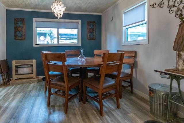 dining room featuring hardwood / wood-style floors, ornamental molding, heating unit, and an inviting chandelier