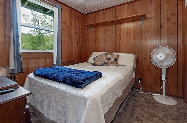 bedroom featuring wooden walls and dark colored carpet