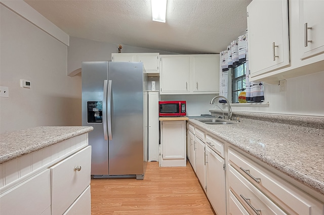 kitchen featuring white cabinetry, vaulted ceiling, stainless steel fridge with ice dispenser, and sink