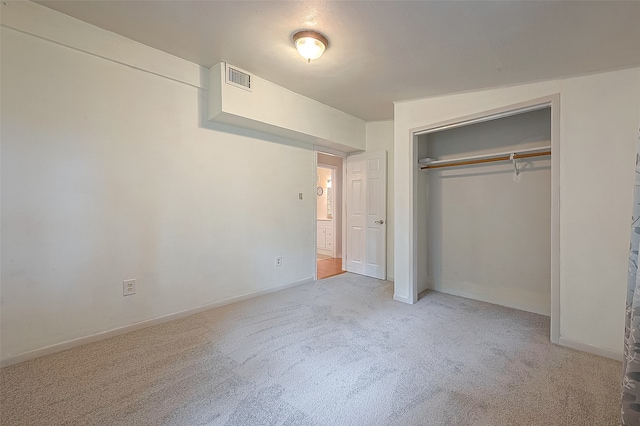 unfurnished bedroom with light colored carpet and a closet