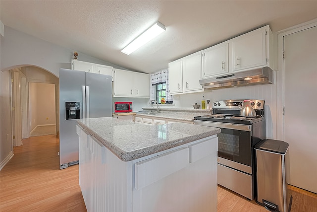 kitchen featuring light wood-type flooring, a center island, vaulted ceiling, white cabinetry, and stainless steel appliances