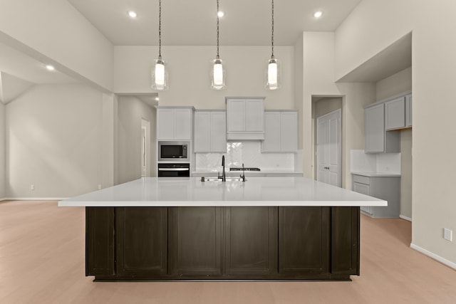 kitchen with a large island, light hardwood / wood-style flooring, oven, and stainless steel microwave