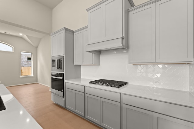 kitchen featuring appliances with stainless steel finishes, light hardwood / wood-style floors, backsplash, and gray cabinetry