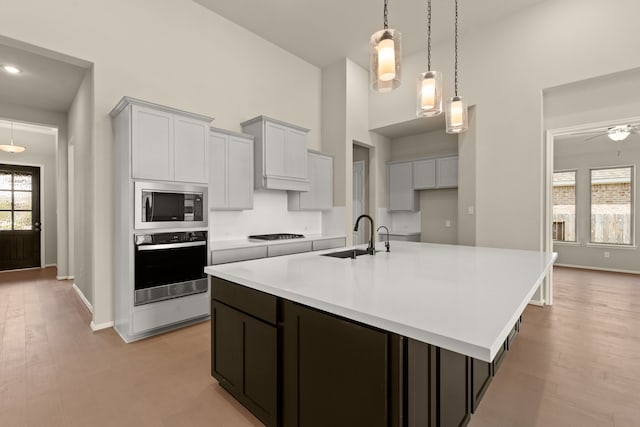 kitchen featuring appliances with stainless steel finishes, sink, light wood-type flooring, and a kitchen island with sink