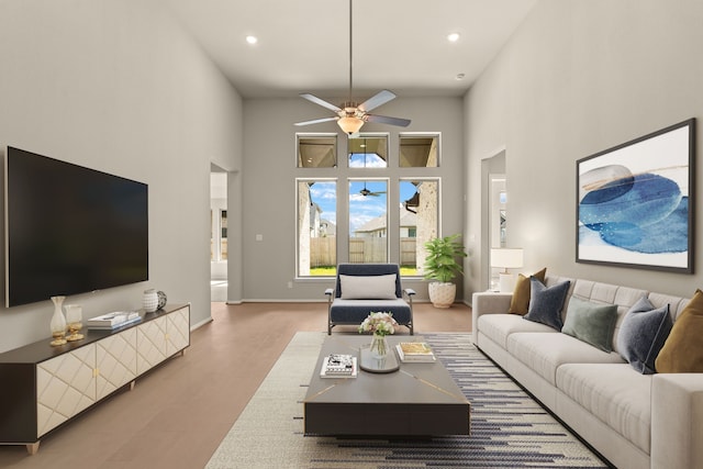 living room with light hardwood / wood-style floors, a towering ceiling, and ceiling fan