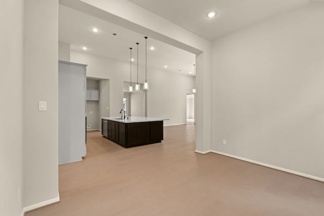 kitchen featuring pendant lighting, light hardwood / wood-style flooring, an island with sink, and sink