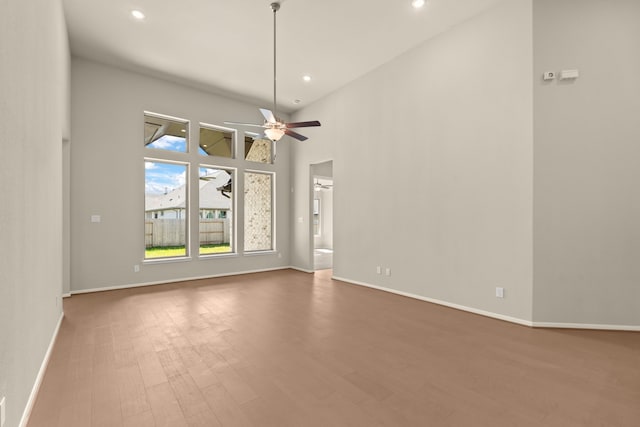 spare room with hardwood / wood-style flooring, a towering ceiling, and ceiling fan