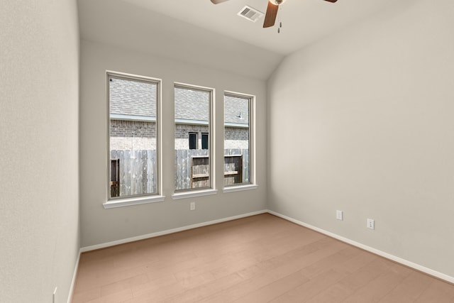 spare room with lofted ceiling, light wood-type flooring, and ceiling fan