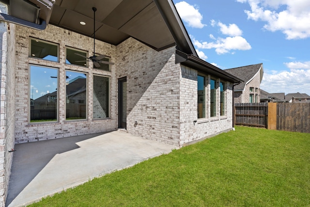 view of side of property with a patio, ceiling fan, and a yard