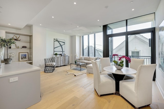 dining area with floor to ceiling windows, recessed lighting, and light wood-type flooring