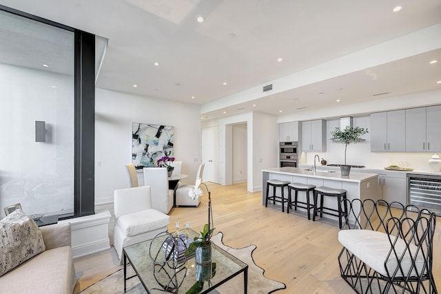 living room with beverage cooler, visible vents, recessed lighting, and light wood-type flooring