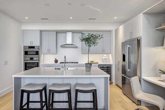 kitchen featuring wine cooler, appliances with stainless steel finishes, wall chimney exhaust hood, and a breakfast bar