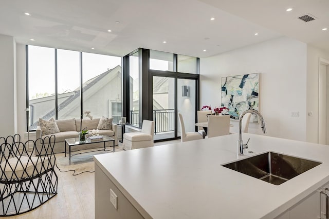 kitchen featuring a healthy amount of sunlight, visible vents, a sink, floor to ceiling windows, and open floor plan