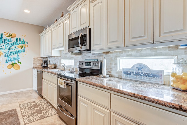 kitchen featuring light tile flooring, appliances with stainless steel finishes, sink, light stone counters, and tasteful backsplash