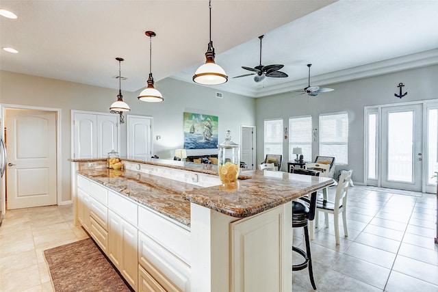 kitchen featuring a center island, ceiling fan, light stone countertops, and decorative light fixtures