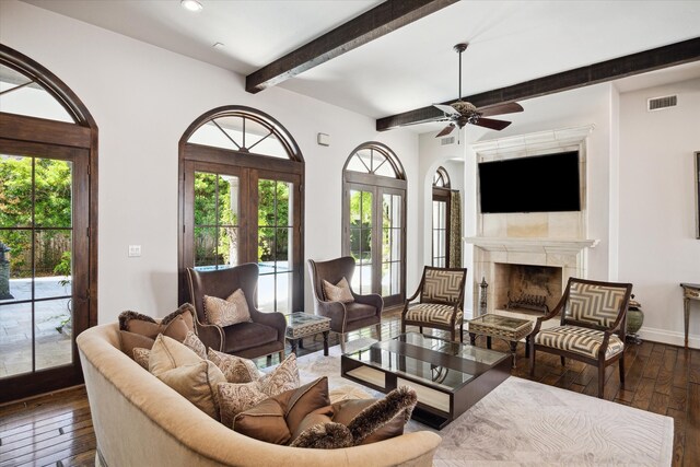 living room featuring french doors, ceiling fan, beamed ceiling, a fireplace, and hardwood / wood-style floors