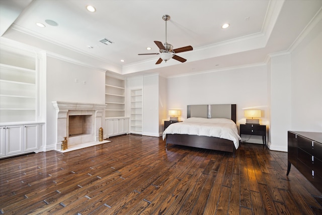 bedroom featuring ceiling fan, crown molding, dark hardwood / wood-style floors, a fireplace, and a raised ceiling