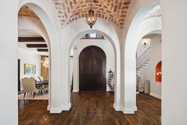 foyer entrance featuring brick ceiling, dark hardwood / wood-style flooring, and an inviting chandelier