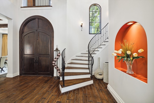 entryway featuring dark hardwood / wood-style flooring and a towering ceiling