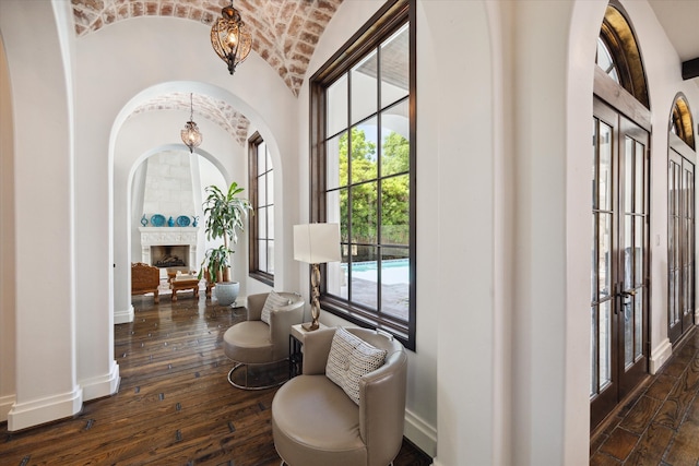 interior space with a wealth of natural light, brick ceiling, dark wood-type flooring, and french doors