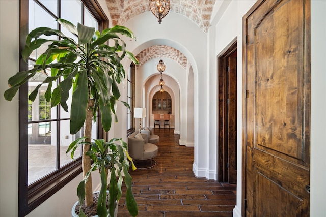 hallway with lofted ceiling, a healthy amount of sunlight, and dark wood-type flooring