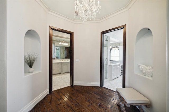 corridor with sink, a chandelier, crown molding, and dark hardwood / wood-style floors