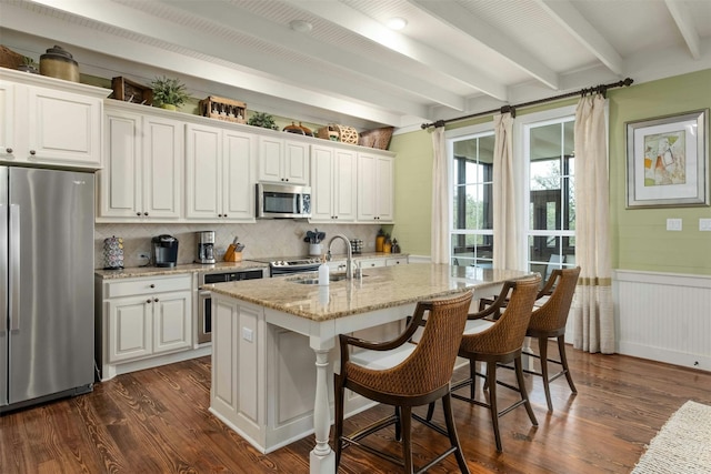 kitchen with appliances with stainless steel finishes, white cabinets, sink, dark wood-type flooring, and beam ceiling