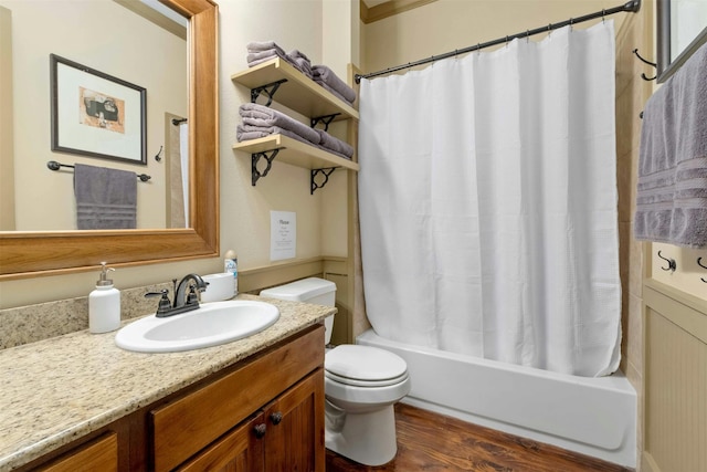 full bathroom with hardwood / wood-style floors, vanity with extensive cabinet space, shower / bath combination with curtain, and toilet