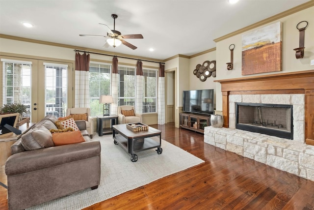 living room featuring ceiling fan, a fireplace, dark wood-type flooring, ornamental molding, and french doors