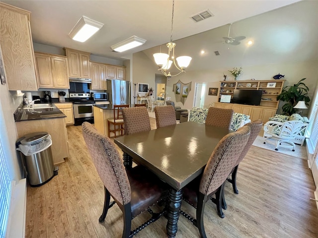 dining room featuring ceiling fan with notable chandelier, sink, and light wood-type flooring