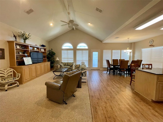 living room with high vaulted ceiling, ceiling fan with notable chandelier, and light wood-type flooring