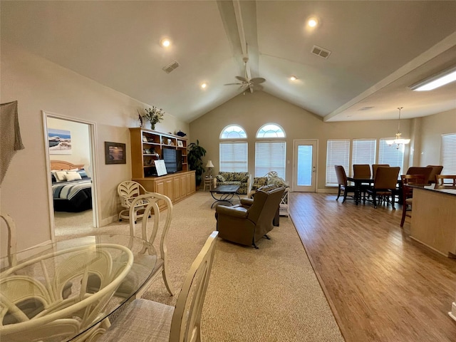 living room featuring ceiling fan with notable chandelier, light hardwood / wood-style flooring, beam ceiling, and high vaulted ceiling