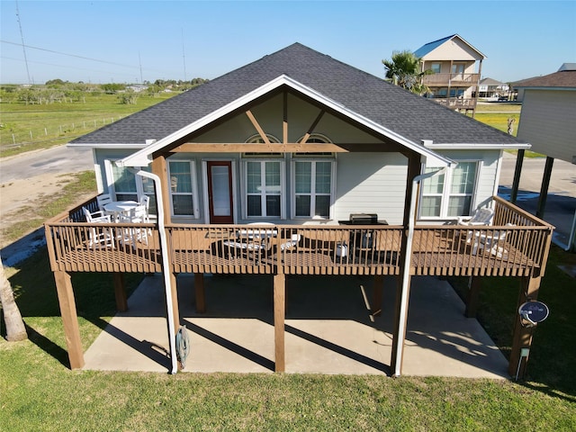 rear view of house featuring a wooden deck and a lawn